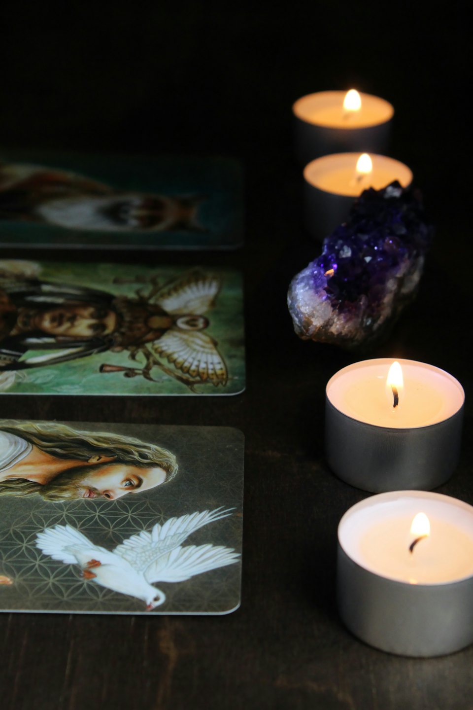 Tarot cards, amethyst, and candles on a wooden table.